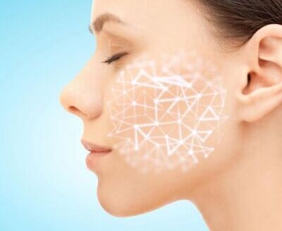 Perfil del rostro de una mujer con los ojos cerrados, con una red geométrica superpuesta en la mejilla sobre un fondo azul, que sugiere análisis de la piel o tecnología para el cuidado de la piel.